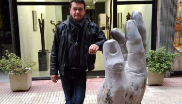 Amancio González junto a la mano en el pasaje de Alfonso V, frente a Ármaga. © Foto: Juan Carlos Pajares.